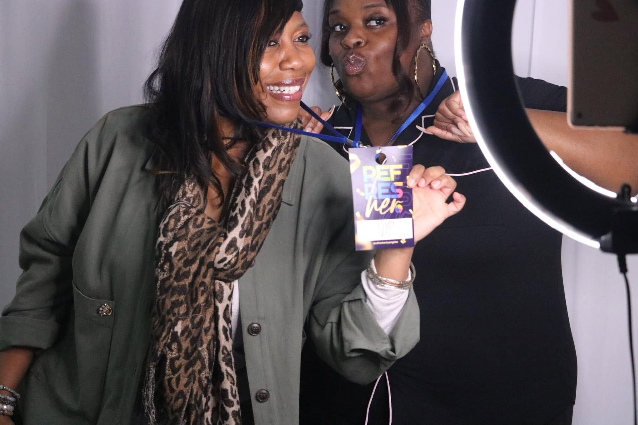 Two RefresHER guests smiling together at a photo booth