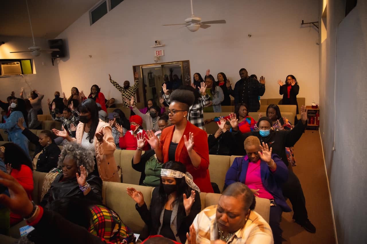 RefresHER attendees standing together with their hands raised in prayer