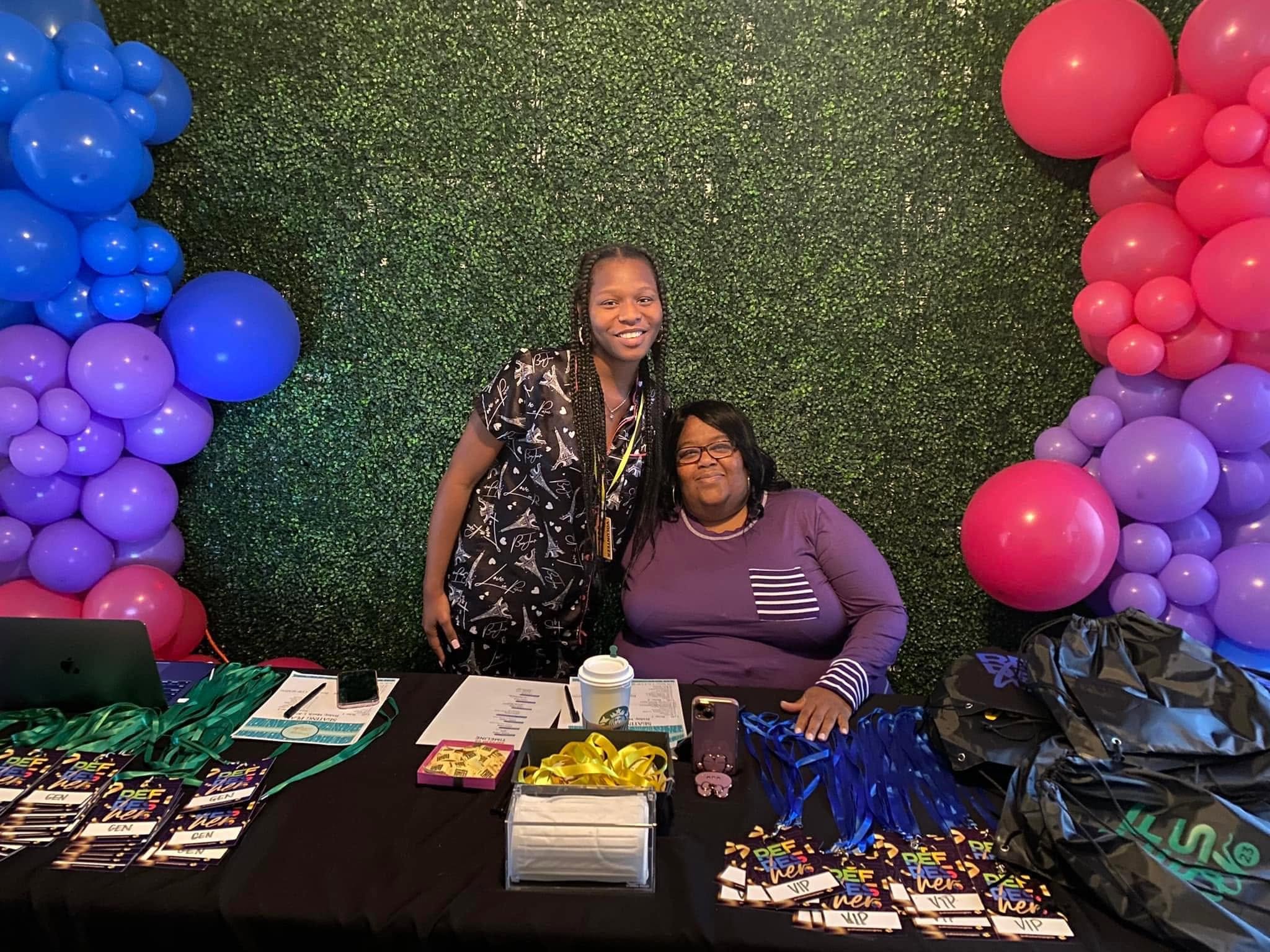 RefresHER welcome team members at a colorful event check-in table