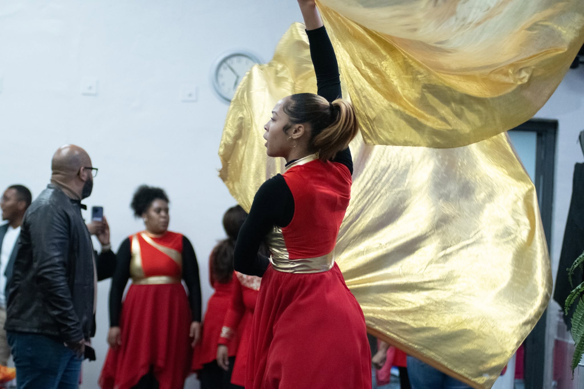 A worship dancer carrying a flowing gold flag at a RefresHER gathering